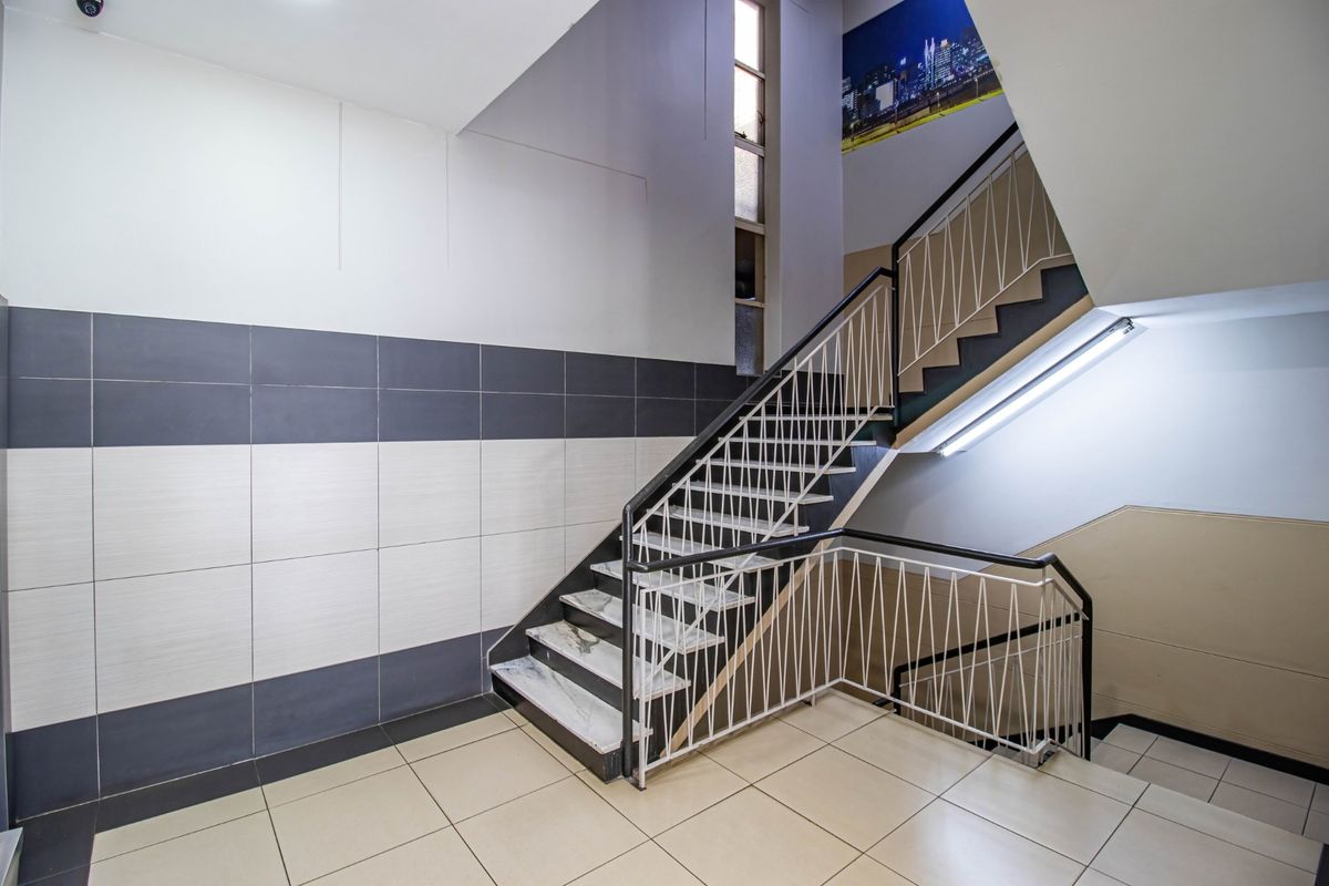 A clean, well-maintained commercial stairwell featuring tiled flooring, modern wall tiling, and a secure metal balustrade.