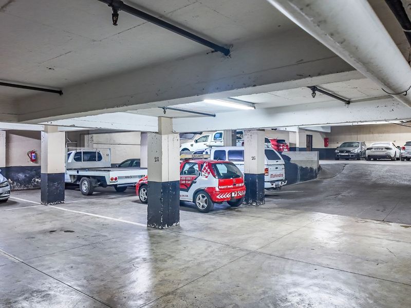 Underground commercial parking garage featuring concrete structural columns, overhead lighting, fire sprinkler system, and marked parking bays.