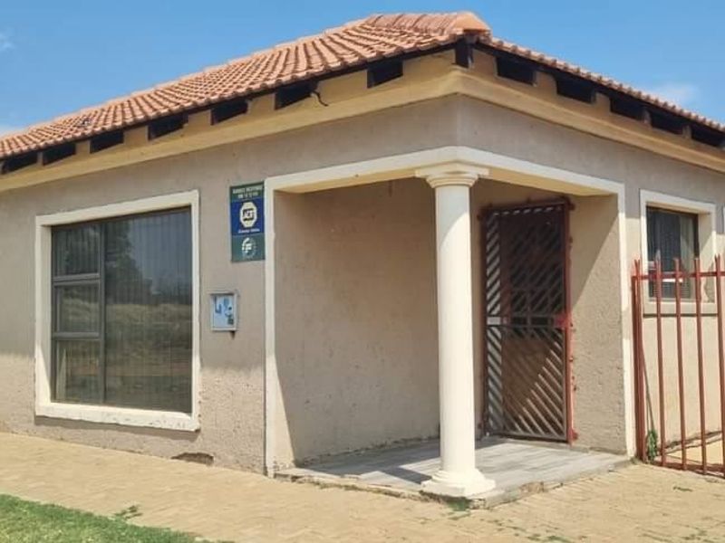 Front exterior view of a single-story house featuring a tiled roof, paved walkway, and security features including bars and a gate.