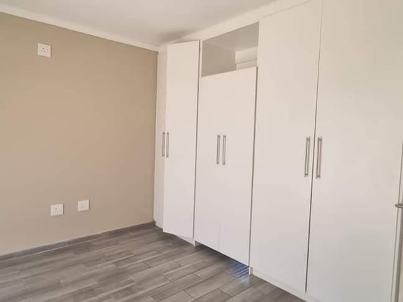 A clean, empty bedroom featuring modern tiled flooring and ample built-in cupboard storage space.