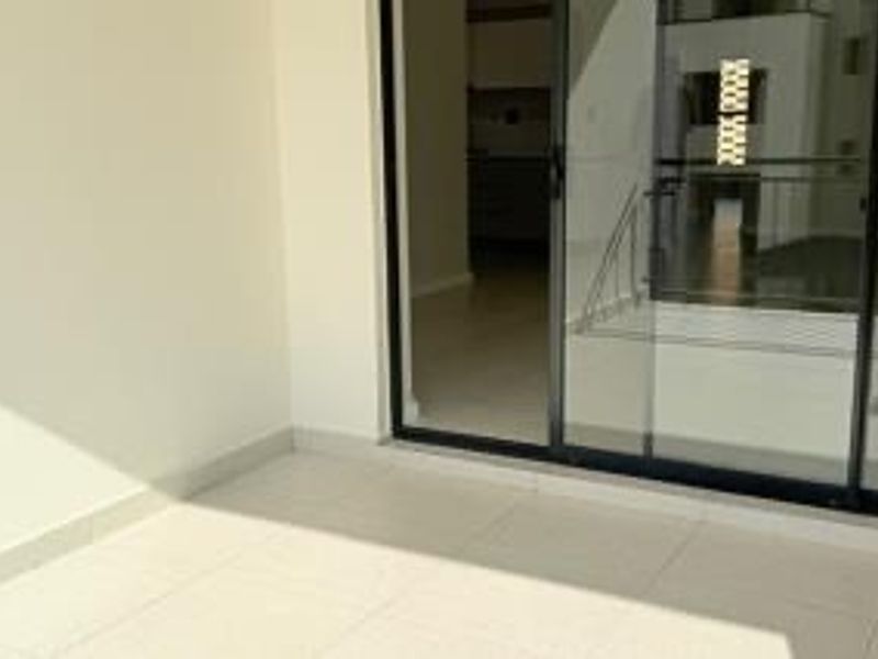A clean, empty balcony featuring tiled flooring and a sliding glass door providing access to the interior living space.