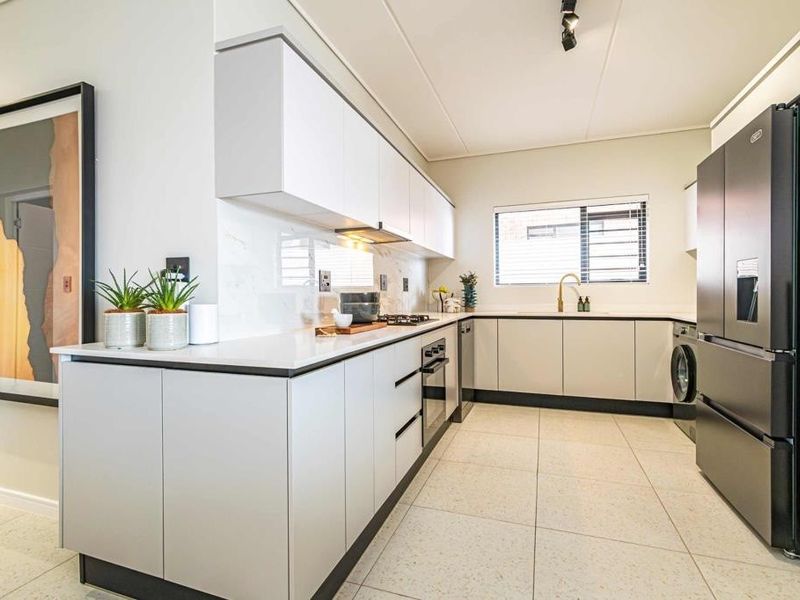 Modern kitchen featuring sleek handleless cabinetry, stone countertops, integrated appliances, and high-quality tiled flooring in a bright, contemporary layout.
