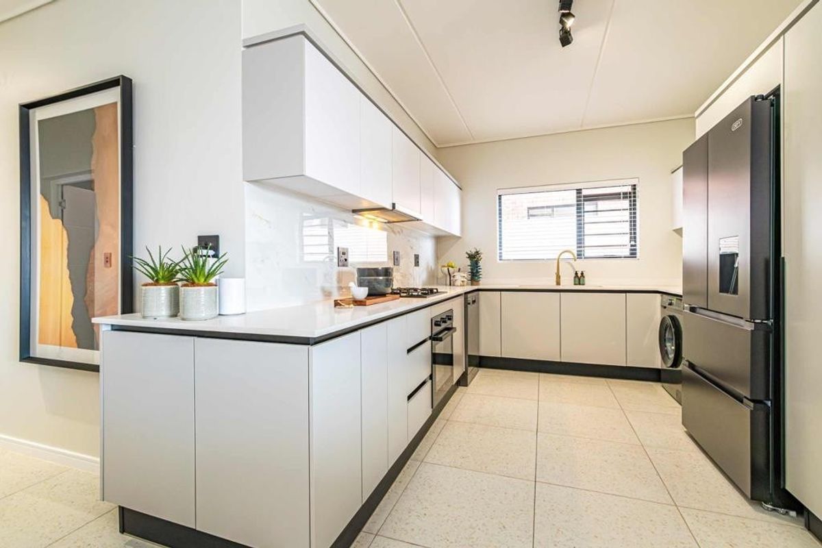 Modern kitchen featuring sleek handleless cabinetry, stone countertops, integrated appliances, and high-quality tiled flooring in a bright, contemporary layout.