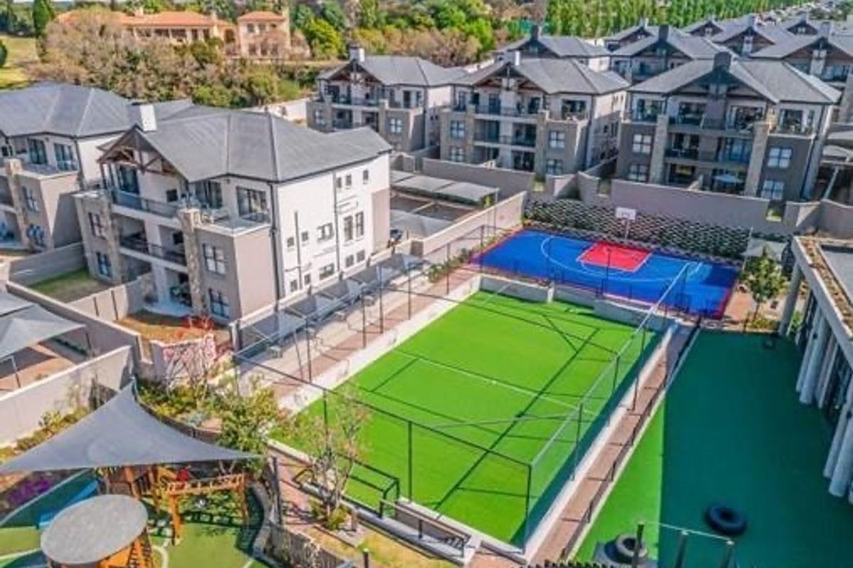 Aerial view of the apartment complex featuring a well-maintained tennis court, basketball court, and landscaped recreational areas.
