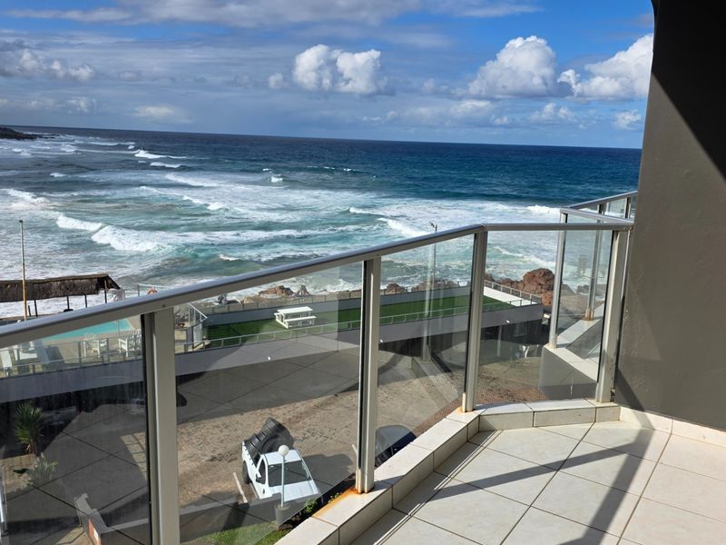 A balcony featuring a glass balustrade with direct, unobstructed views of the ocean and coastline.