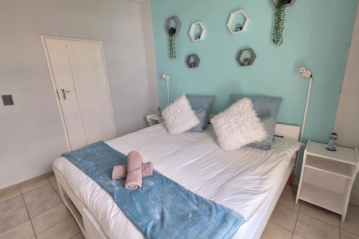 A bedroom featuring tiled flooring, a painted accent wall, and wall-mounted lighting fixtures.