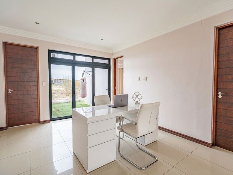 A bright home office featuring tiled flooring, recessed lighting, and a sliding glass door providing direct access to the outdoor area.