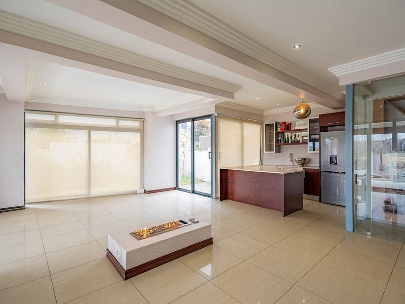 Spacious open-plan living and kitchen area featuring tiled floors, a central built-in fireplace, modern cabinetry, and large sliding doors leading to the exterior.