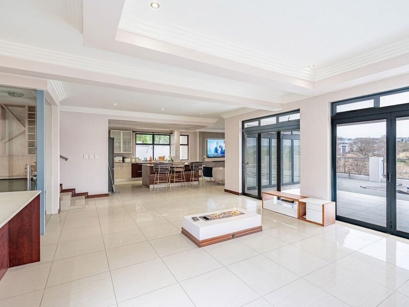 Spacious open-plan living area featuring high-gloss tiled floors, recessed ceiling details, a modern kitchen island, and seamless access to the outdoor patio through bi-fold doors.