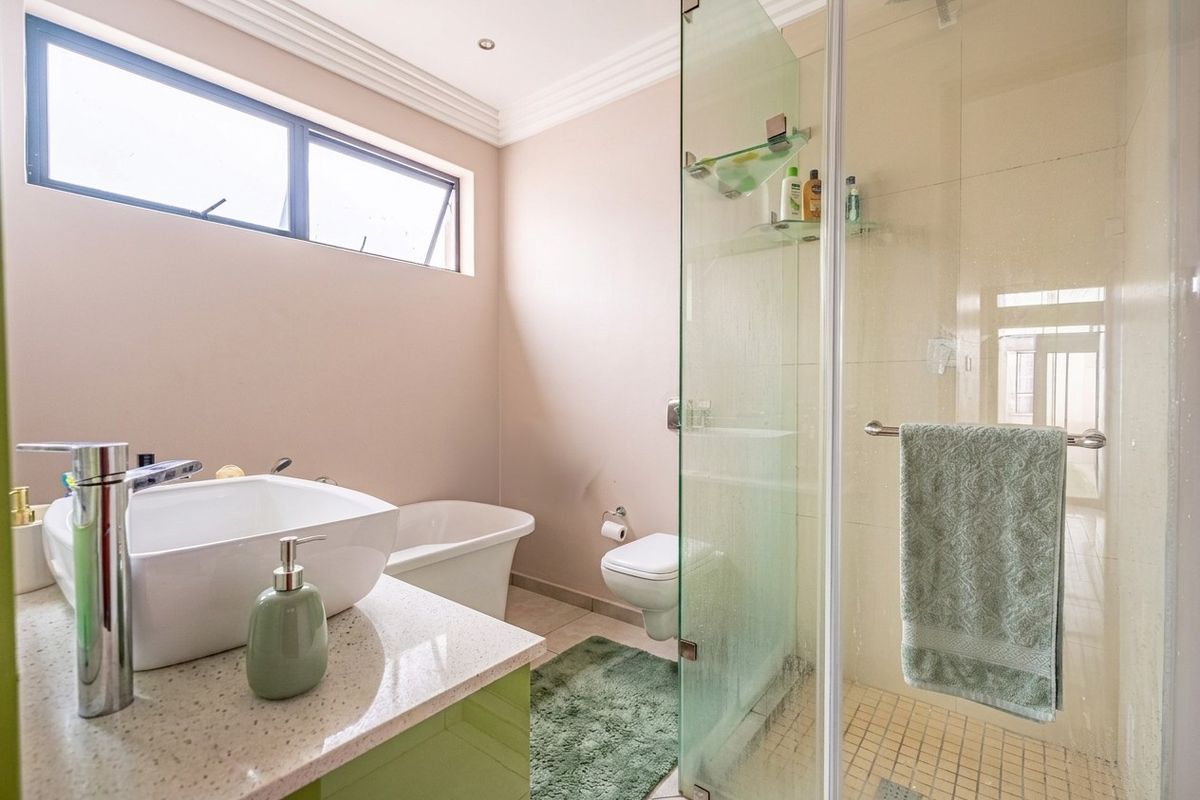 Modern bathroom featuring a freestanding bathtub, glass-enclosed shower, wall-mounted toilet, and a stylish vessel sink set on a stone vanity countertop.