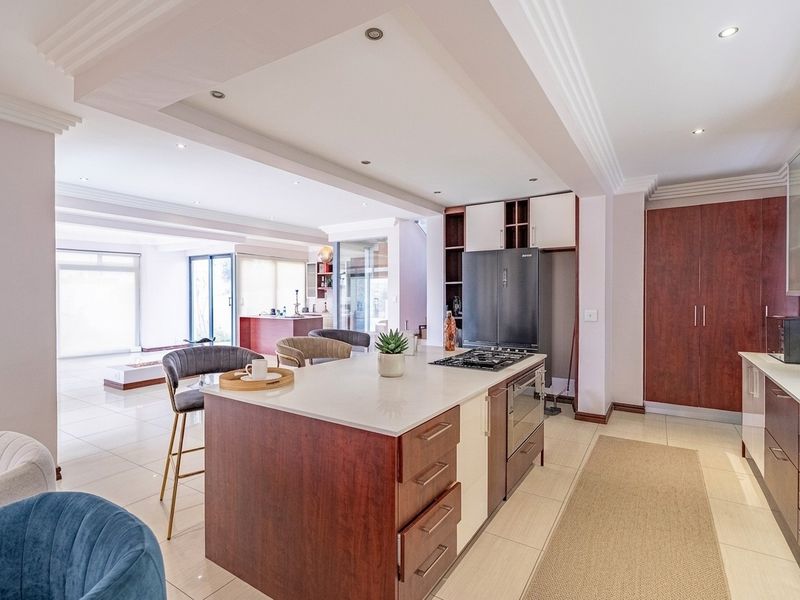 Spacious open-plan kitchen featuring a central island with built-in cooktop and oven, complemented by modern cabinetry and recessed ceiling lighting.