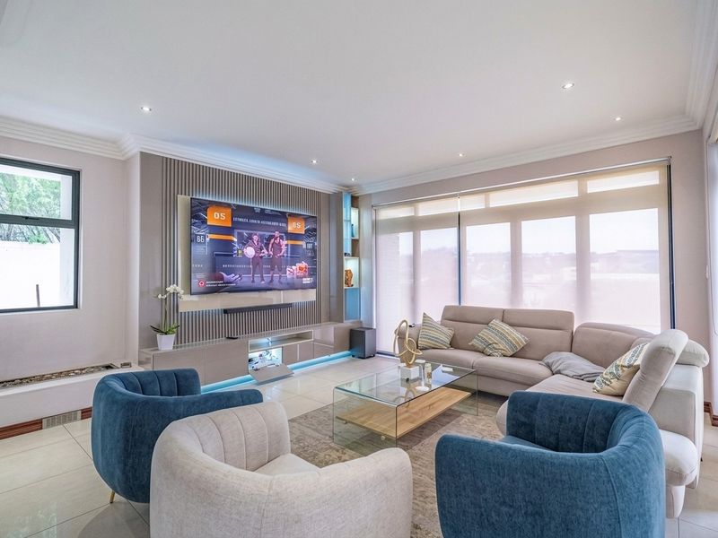 Modern living room featuring a custom built-in media unit with slatted wall paneling, recessed lighting, and large windows with roller blinds.