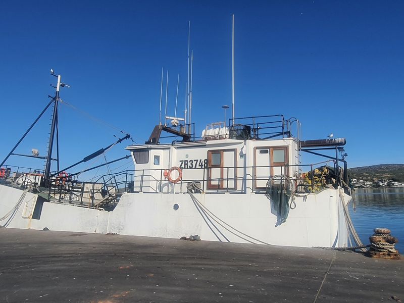 A view of a fishing vessel docked at a concrete pier.