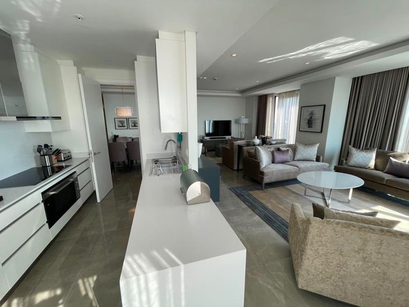 Spacious open-plan living area featuring a modern kitchen with stone countertops, integrated appliances, and seamless flow into the comfortable lounge space.