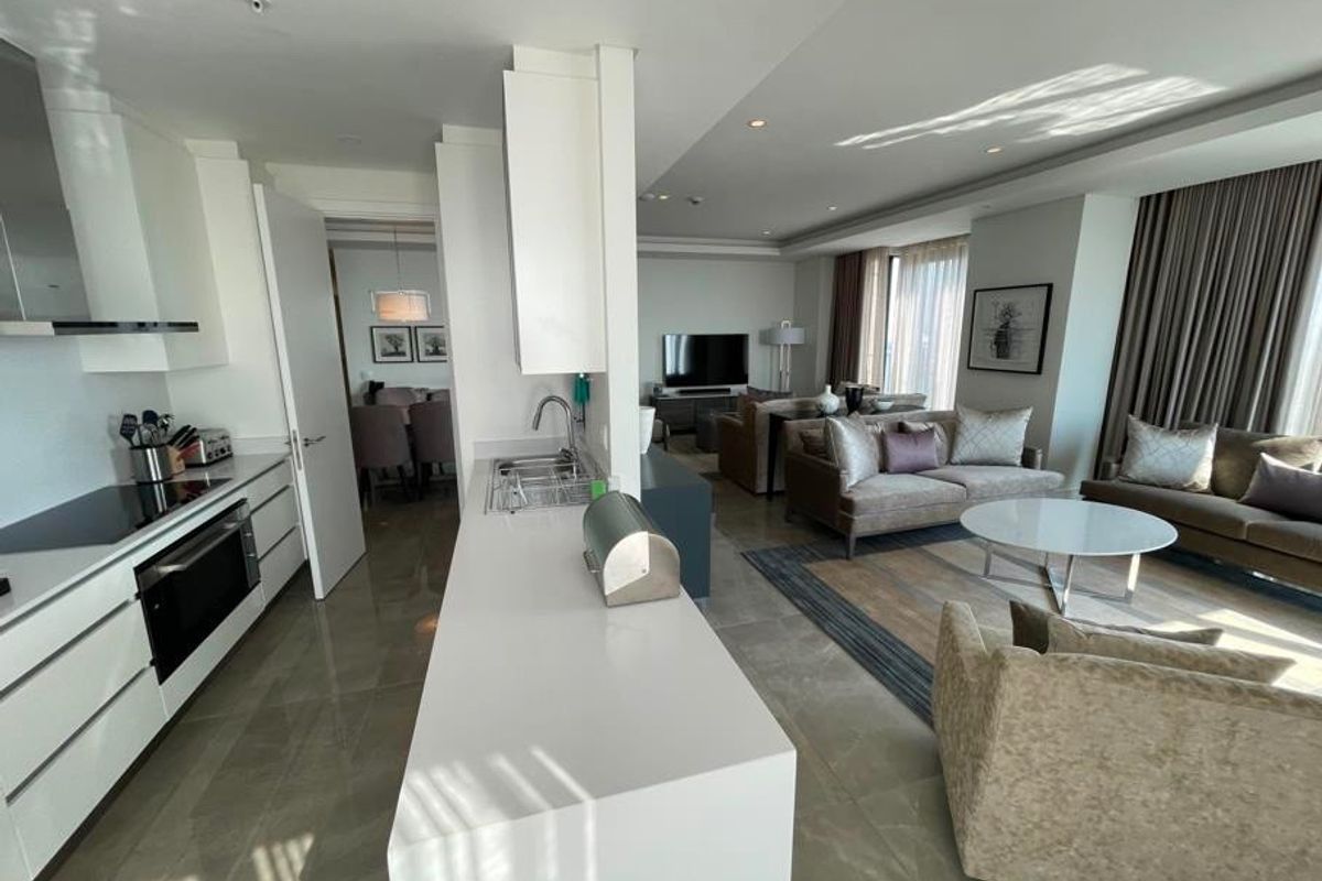 Spacious open-plan living area featuring a modern kitchen with stone countertops, integrated appliances, and seamless flow into the comfortable lounge space.
