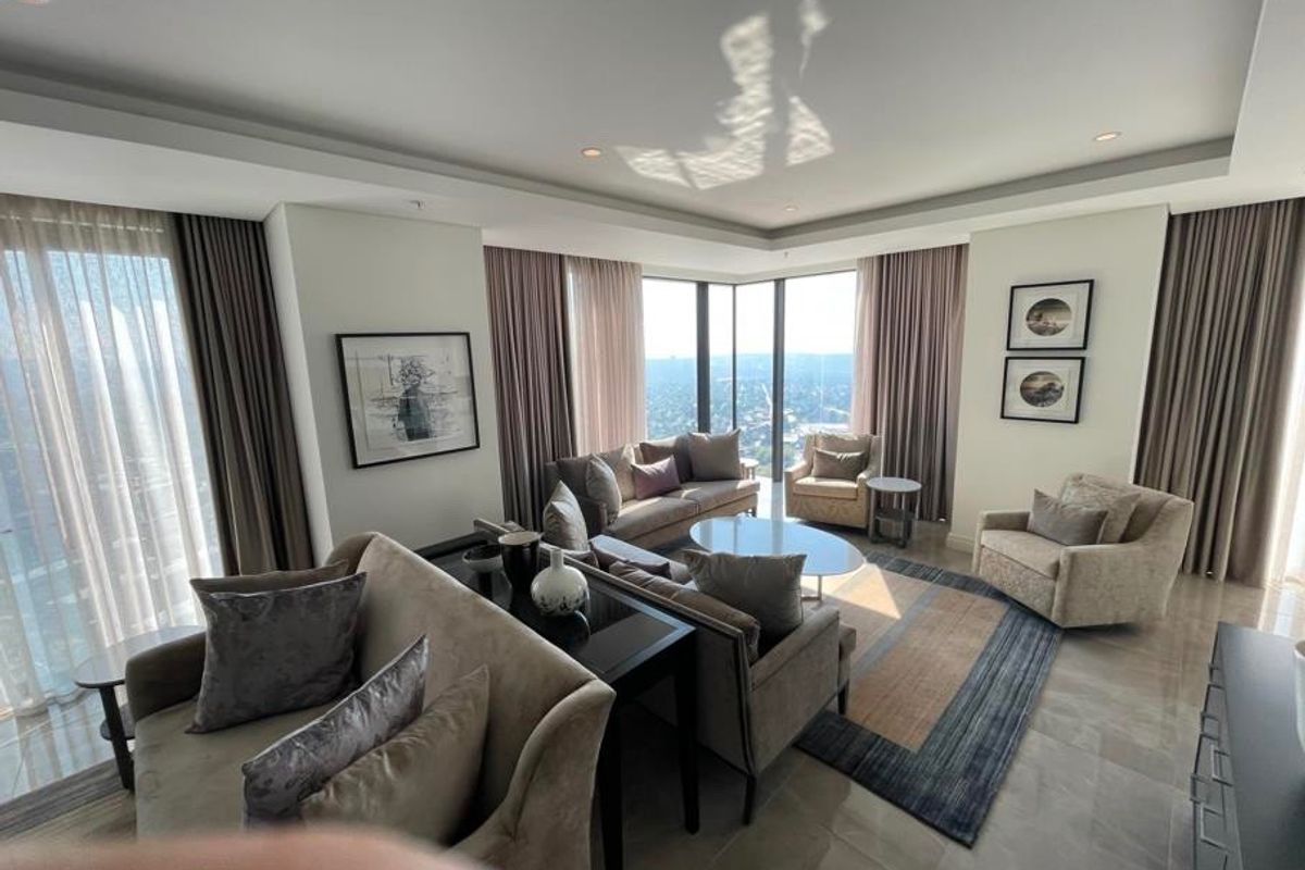 Spacious living room featuring floor-to-ceiling windows with panoramic views, recessed ceiling lighting, and high-quality stone flooring in a modern apartment setting.