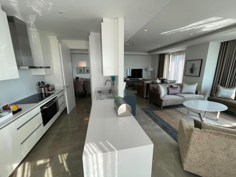 Modern open-plan living area featuring a sleek kitchen with stone countertops, integrated appliances, and seamless flow into the comfortable lounge space.