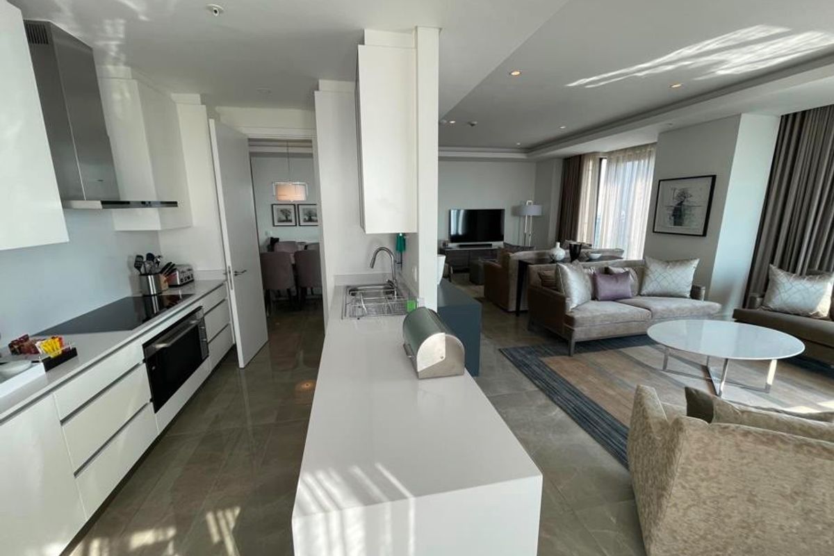 Modern open-plan living area featuring a sleek kitchen with stone countertops, integrated appliances, and seamless flow into the comfortable lounge space.