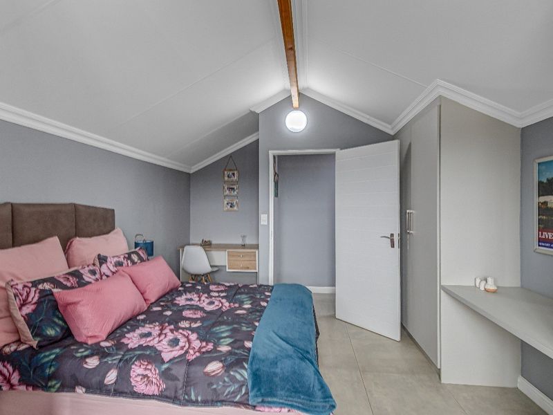 A well-maintained bedroom featuring a vaulted ceiling, built-in cupboards, and neutral tiled flooring, offering a clean and functional living space.