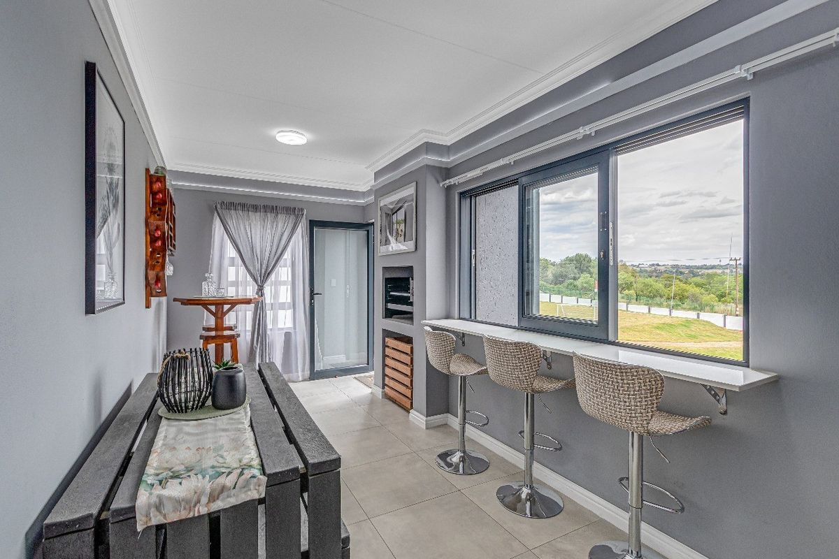 A modern living area featuring tiled floors, a built-in fireplace, and a breakfast bar overlooking the exterior view.