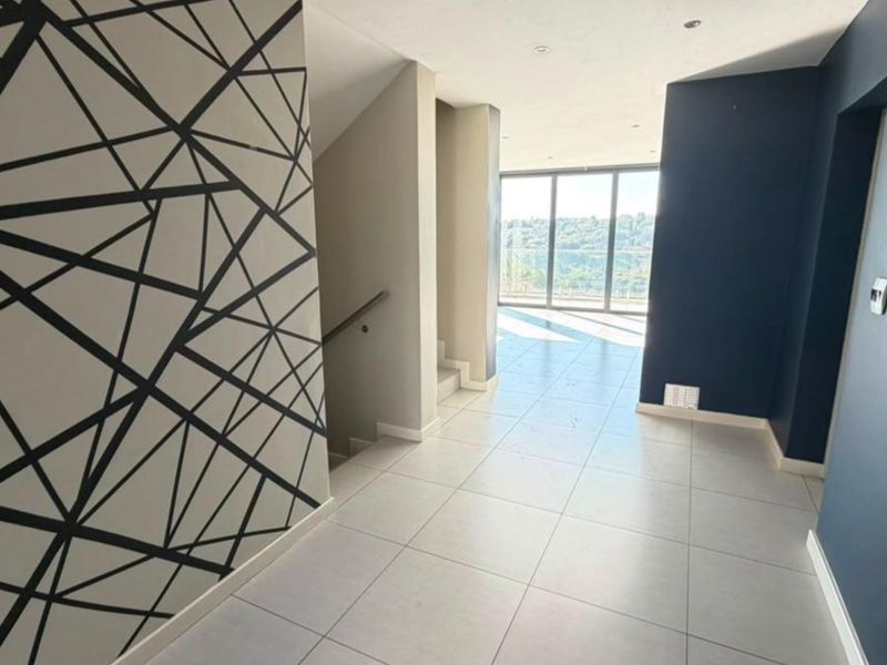 Spacious, modern hallway featuring tiled flooring, a staircase, and large sliding glass doors that provide natural light and views.
