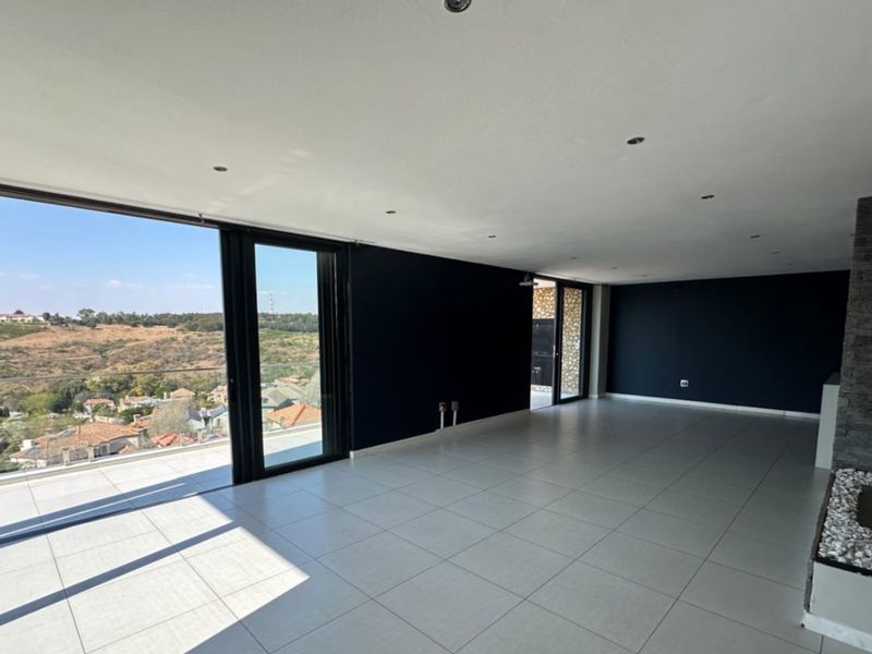 Spacious, modern living area featuring large format floor tiles, a stone-clad fireplace, and expansive sliding glass doors opening to a scenic balcony.