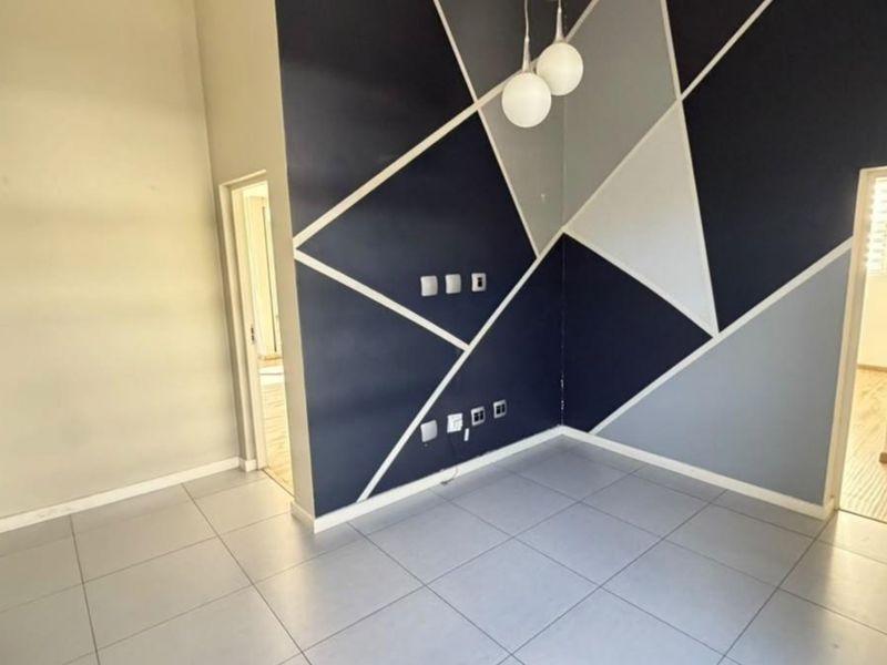 An empty living area featuring large format floor tiles and a modern geometric accent wall with integrated electrical and data points.