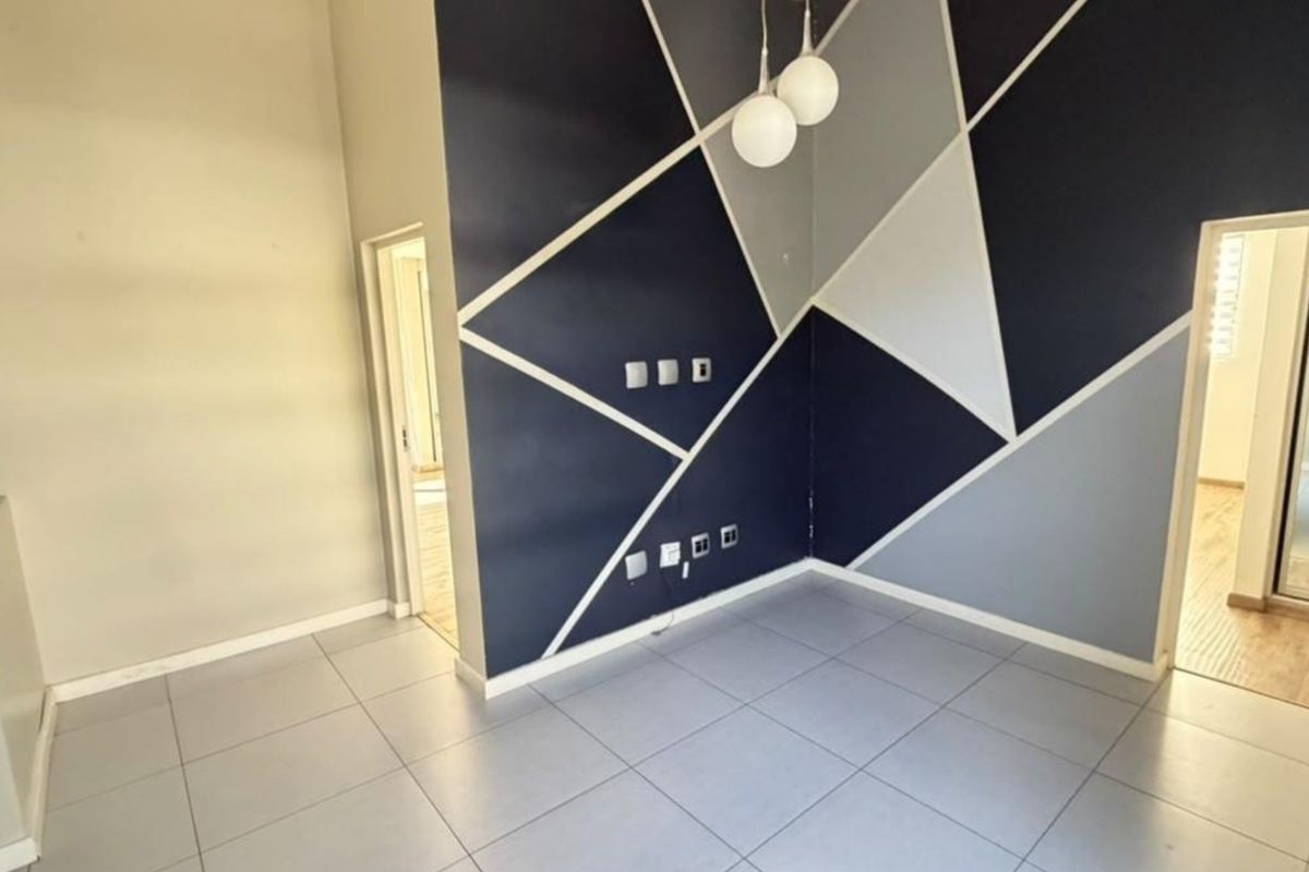 An empty living area featuring large format floor tiles and a modern geometric accent wall with integrated electrical and data points.