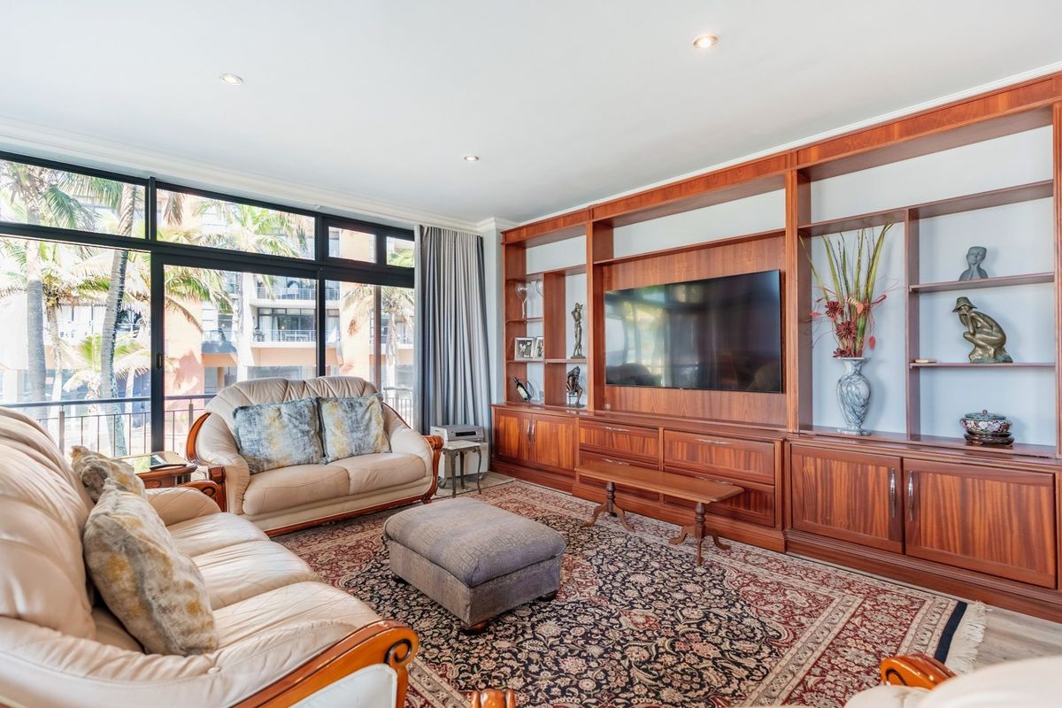 Spacious living room featuring extensive built-in wooden cabinetry and large sliding glass doors that provide ample natural light and access to the balcony.