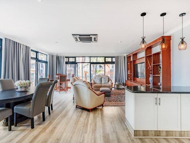 Spacious open-plan living and dining area featuring modern laminate flooring, built-in cabinetry, and large glass sliding doors leading to an outdoor space.