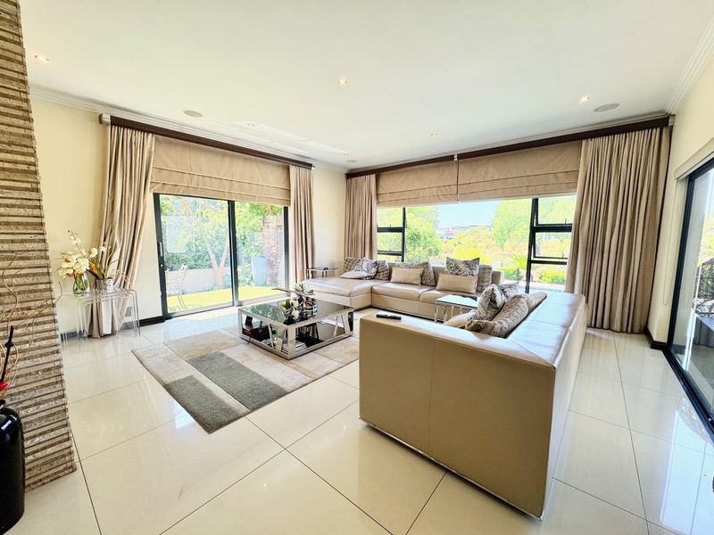 Spacious living room featuring large format floor tiles, a stone-clad feature wall, and expansive sliding glass doors providing ample natural light and garden access.