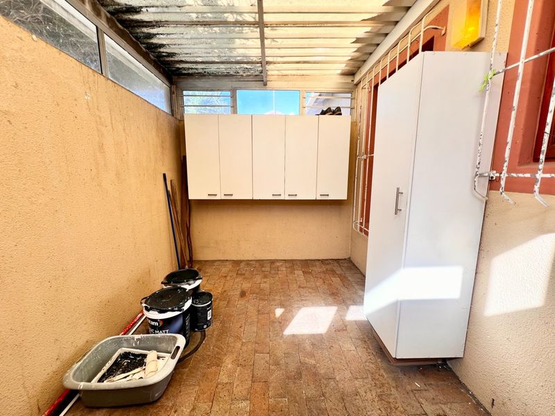 A covered utility or storage area featuring brick flooring, wall-mounted cabinetry, and translucent roof sheeting, providing a functional space for household storage.