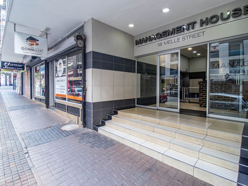 Front entrance of Management House at 38 Melle Street, featuring glass doors, tiled steps, and a modern tiled facade with street-level access.