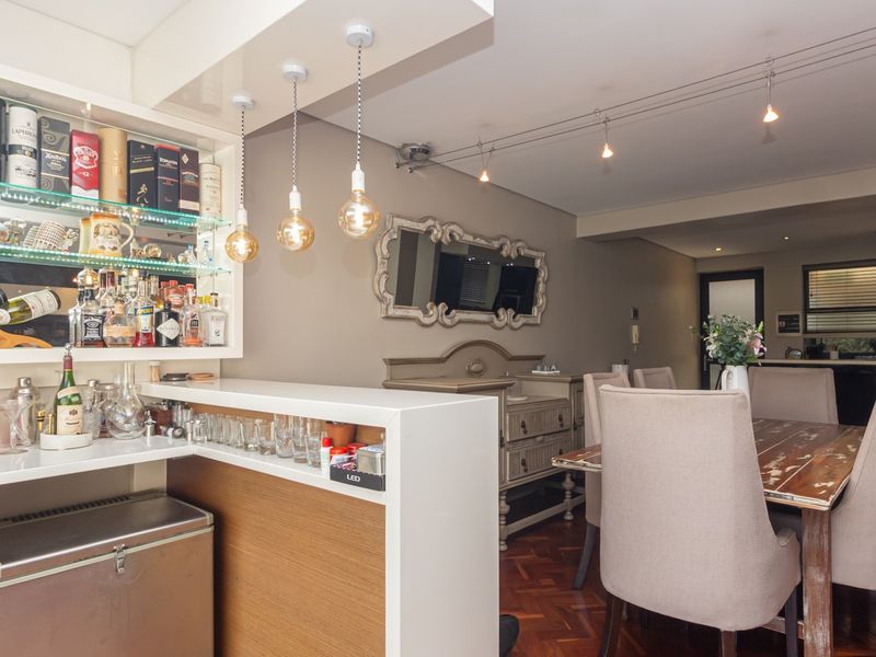 Open plan living and dining area featuring a built-in bar with integrated wine storage, parquet flooring, and modern pendant and track lighting.