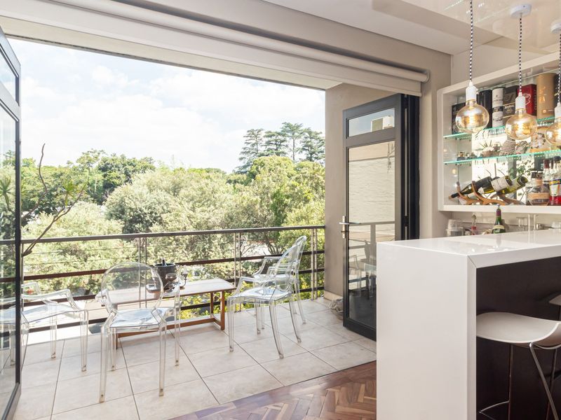 A modern balcony featuring bi-fold doors, stainless steel balustrades, and a built-in bar area, offering a seamless transition to outdoor living.