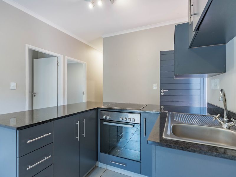 Modern kitchen featuring dark grey cabinetry, granite countertops, stainless steel sink, and integrated electric oven and hob.