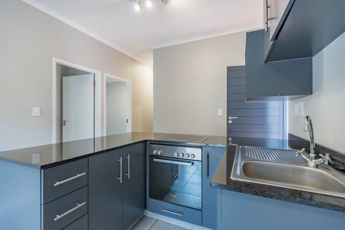 Modern kitchen featuring dark grey cabinetry, granite countertops, stainless steel sink, and integrated electric oven and hob.