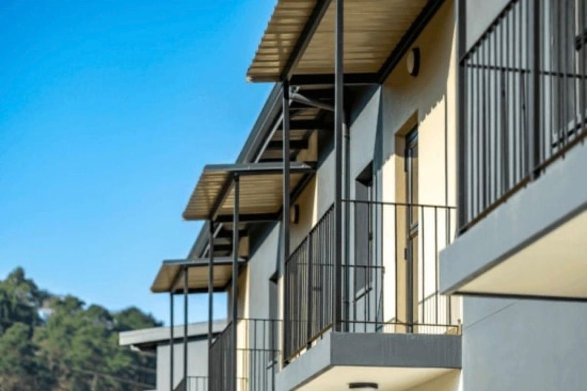 Exterior view of apartment building featuring modern balconies with metal railings and protective roof overhangs.