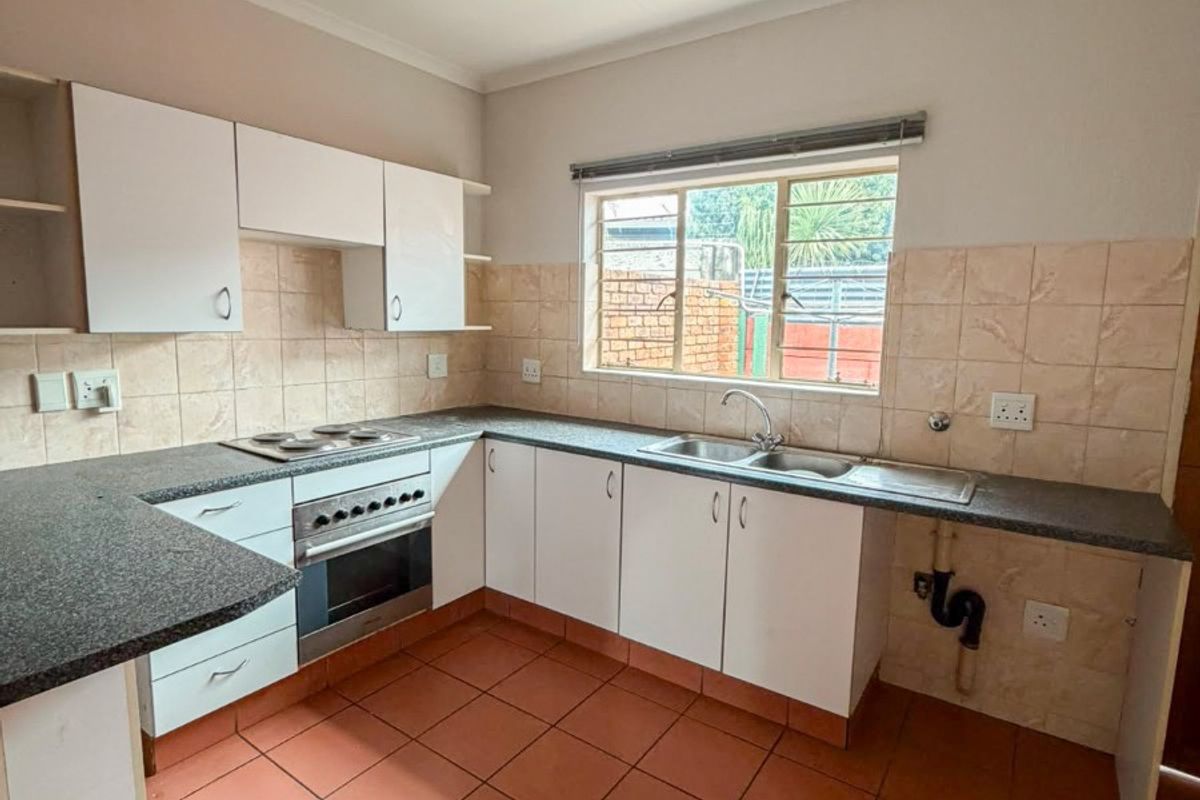 A functional kitchen featuring built-in cabinetry, laminate countertops, a built-in oven with hob, and ceramic floor tiles, requiring some cosmetic updates.