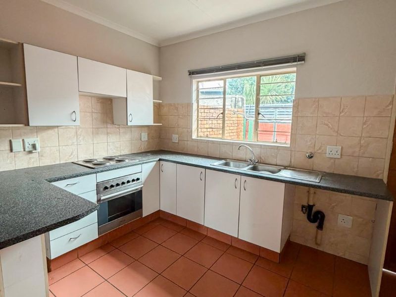 A functional kitchen featuring built-in cabinetry, laminate countertops, a built-in oven with hob, and ceramic floor tiles, requiring some cosmetic updates.