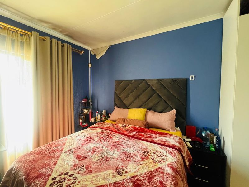 A bedroom featuring blue walls, a built-in wardrobe, and a window with curtain fixtures. The room requires minor cosmetic repairs to the wall finish.