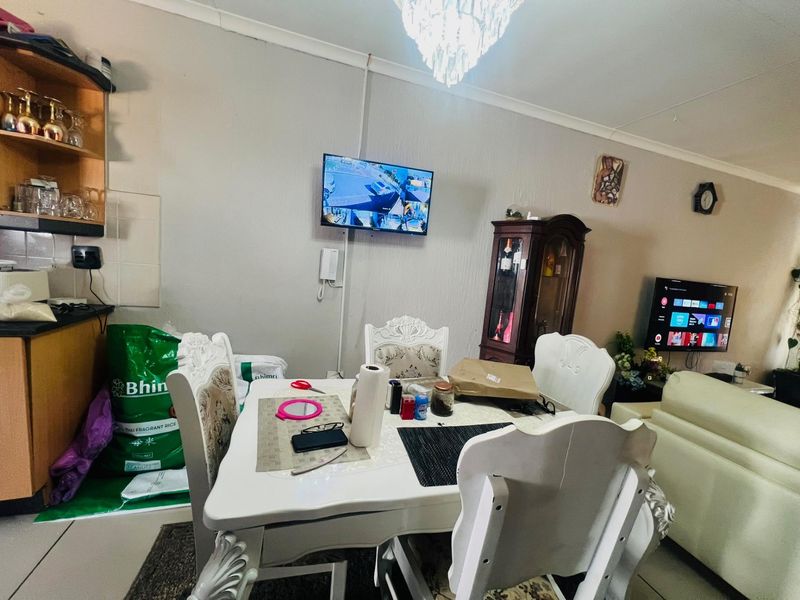 Open plan living and dining area featuring tiled flooring, coved ceilings, and a central crystal chandelier.