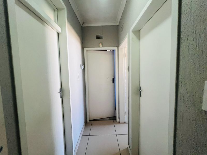 A functional interior hallway featuring tiled flooring and multiple internal doors providing access to various rooms within the property.