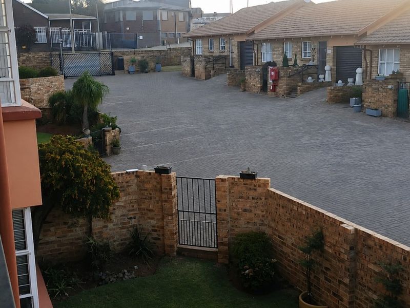 Elevated view of a residential complex courtyard featuring a private garden area, brick boundary walls, and paved communal driveway access.