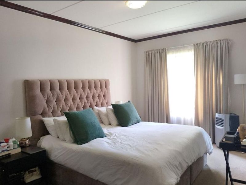 A well-lit bedroom featuring crown molding and a large window with curtains, providing a comfortable and functional living space.