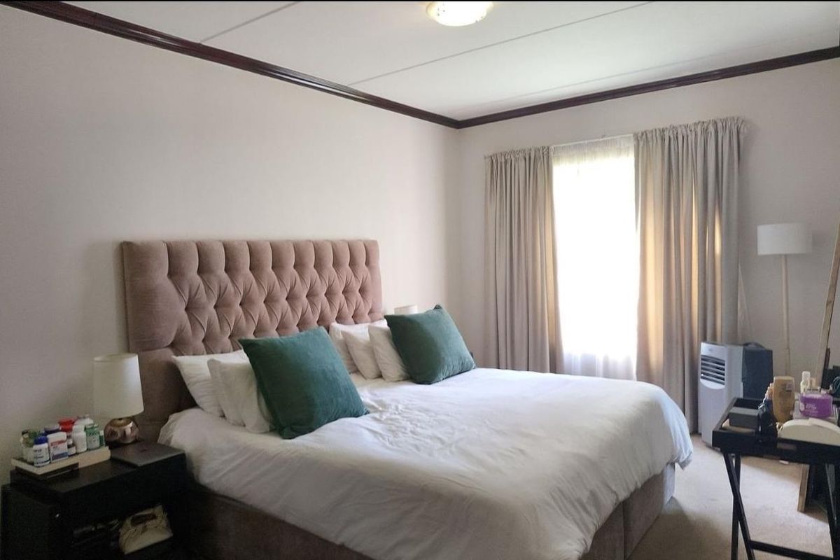 A well-lit bedroom featuring crown molding and a large window with curtains, providing a comfortable and functional living space.