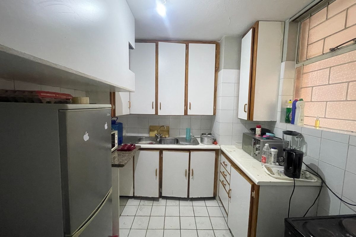A functional kitchen featuring white cabinetry, tiled backsplash, and tiled flooring, offering a dated aesthetic with potential for modern renovation.