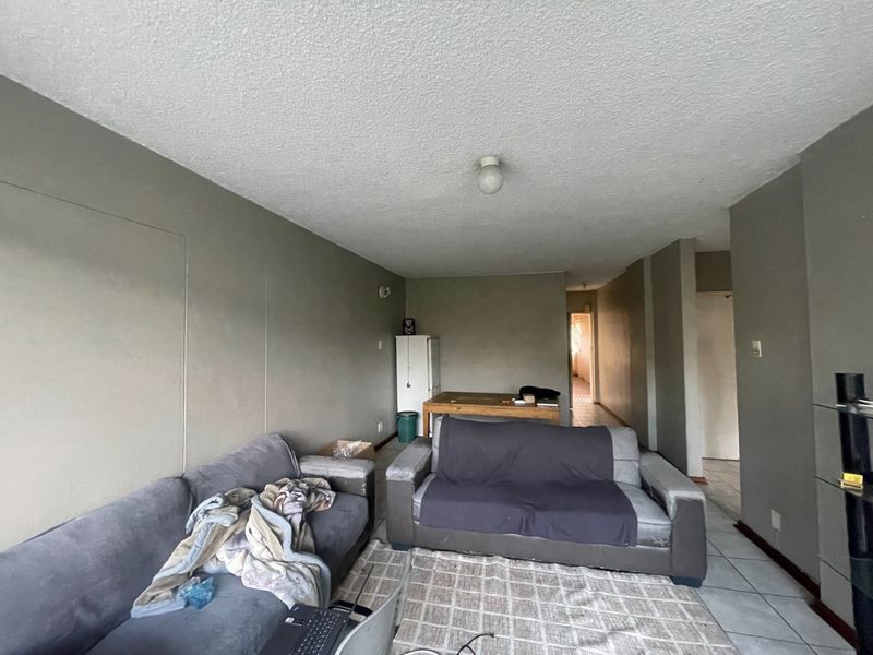 A living room area featuring tiled flooring and neutral wall tones, offering a functional space ready for modernization and cosmetic updates.