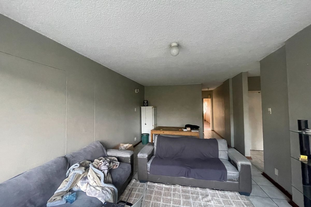 A living room area featuring tiled flooring and neutral wall tones, offering a functional space ready for modernization and cosmetic updates.