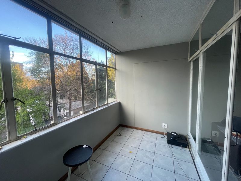 An enclosed balcony or sunroom featuring large glass windows, tiled flooring, and neutral wall finishes, offering a bright and versatile space.
